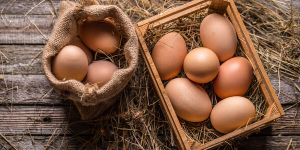 Bunch of fresh brown eggs in a wooden crate and in burlp sack