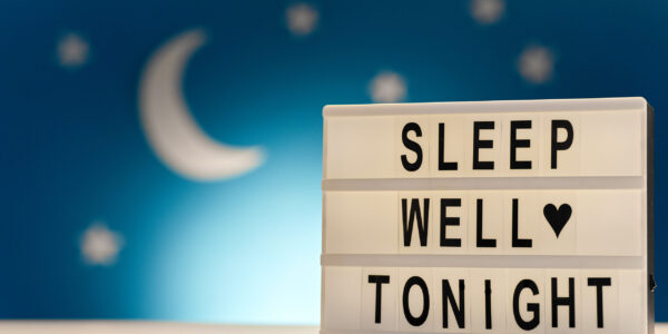sleeping and bedtime concept - close up of customizable light box with sleep well tonight words over moon and night stars on blue background